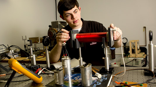 Student makes adjustments to electrical device in lab